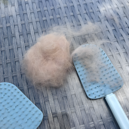 Blauwe FurLisse-borstels met een pluk uitgekamd kattenhaar ernaast